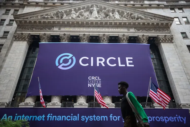 El logotipo de Circle, proyectado en la Bolsa de Nueva York durante la cotización de CRCL, con banderas y un peatón en primer plano